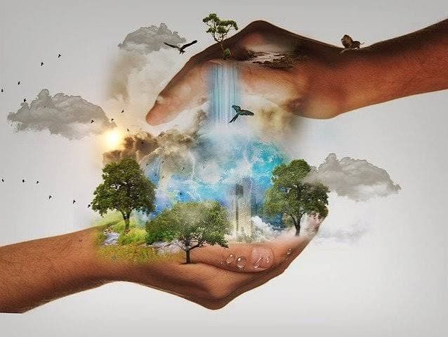 Two hands surrounding a small world with trees, a waterfall, birds and clouds